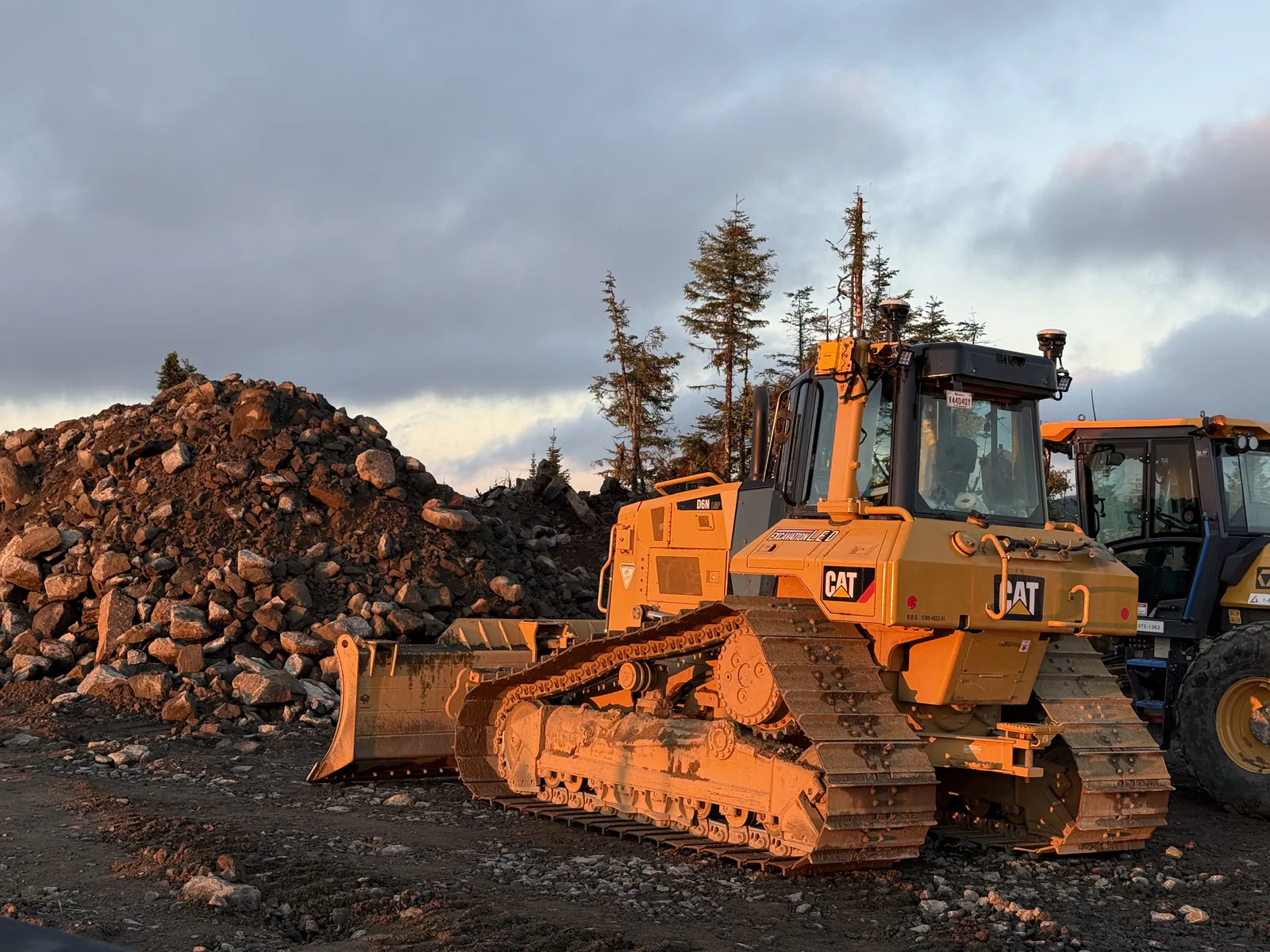 Bouteur au lever du jour — Bouteur Caterpillar devant une réserve de roc au lever du jour.