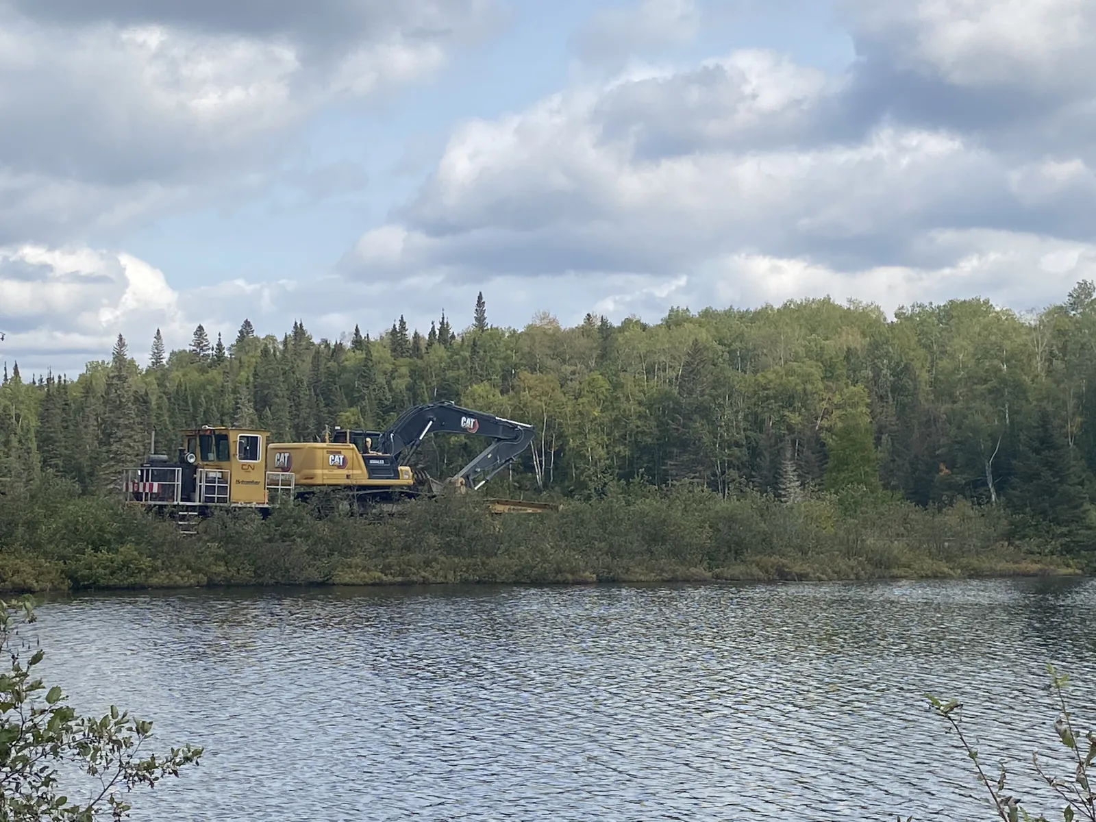 Voie ferrée au bord d'un lac — Machinerie lourde sur une voie ferrée longeant un lac.