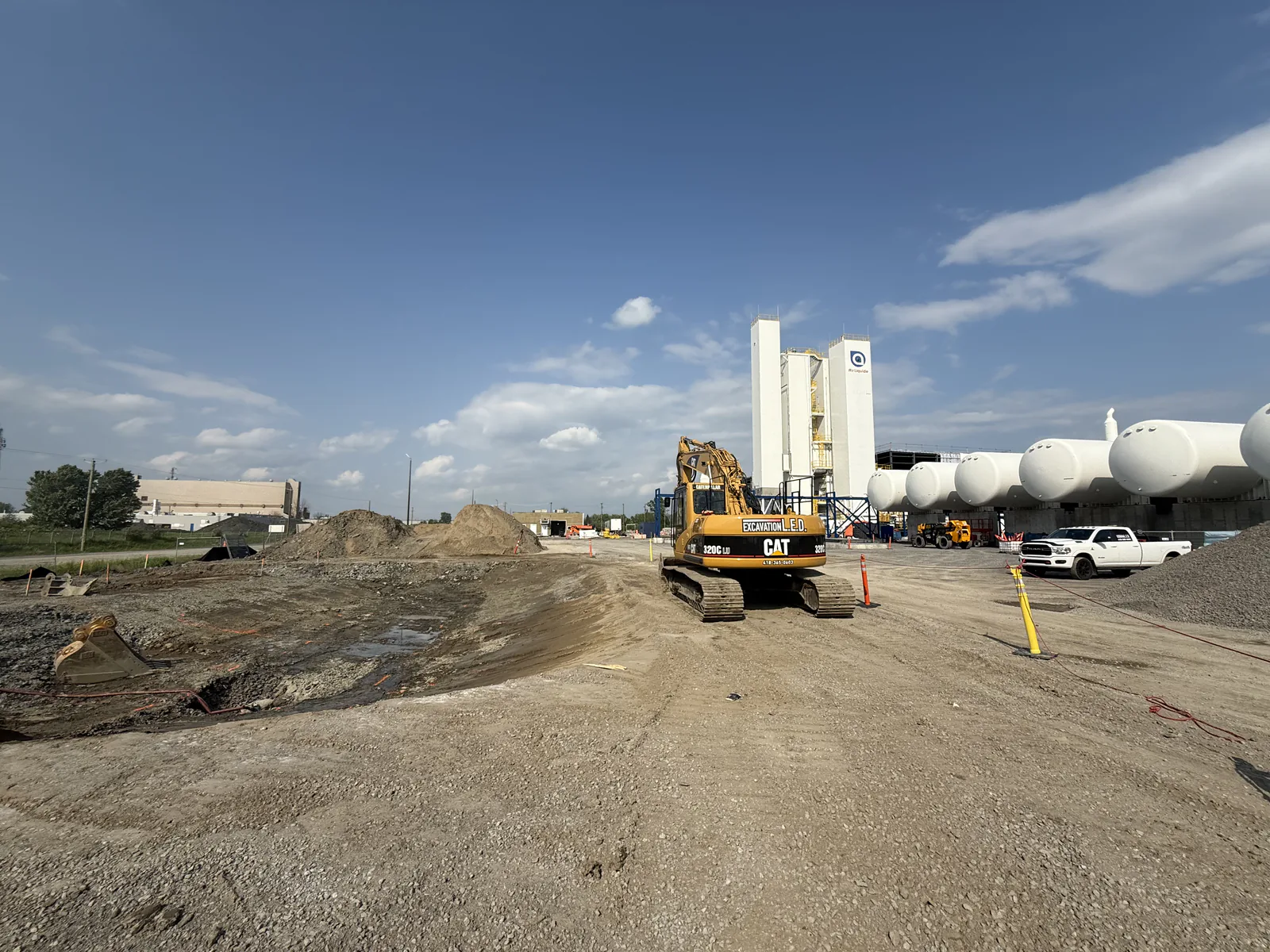 Chantier industriel — Pelle Caterpillar sur un chantier industriel, près de silos.