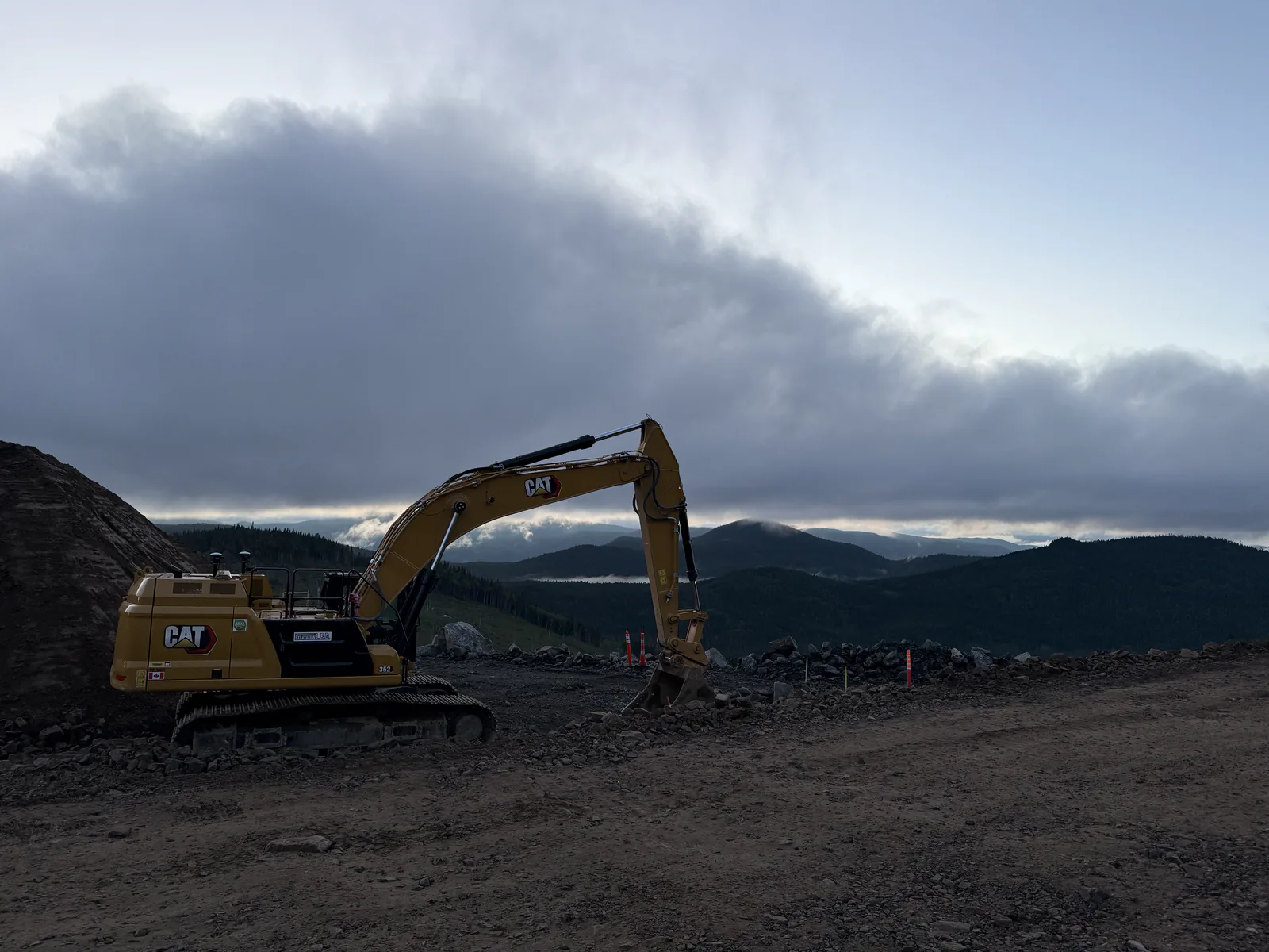 Chantier en montagne — Pelle Caterpillar sur un chantier, montagnes dans la brume.