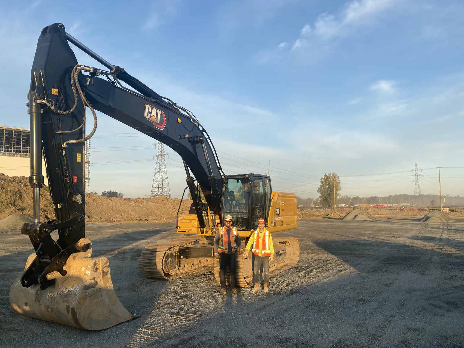 Pelle neuve et opérateurs — Pelle Caterpillar neuve et deux opérateurs sur un chantier.